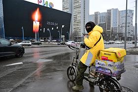 Акция памяти жертв теракта в подмосковном концертном зале 'Крокус Сити Холл'. Изображение горящей свечи и надписи 'Скорбим 22.03.2024' на экране торгового центра 'Рио' на пересечении Ленинского проспекта и улицы Обручева