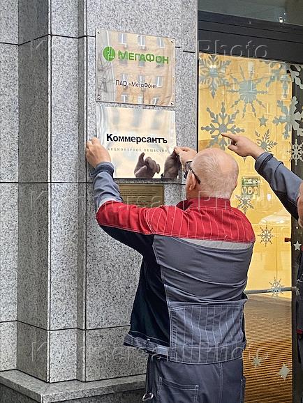 Genre photography. Installation of a Kommersant JSC sign at the entrance to the Oruzheyny business center