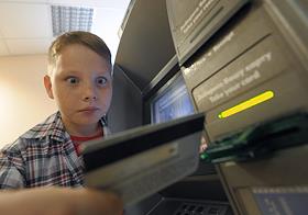 Ребенок пользуется банкоматом в здании ИД 'КоммерсантЪ'